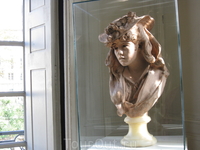 Эта головка молодой девушки из розового мрамора, находится под стеклом.