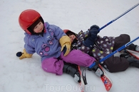 Инструктор обучает детей катанию на лыжах