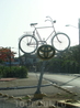 это памятник велосипеду, через окно микроавтобуса)