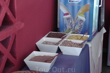 Четыре сорта мюсли, на переднем плане - какао, за ними - холодильник с йогуртами.