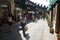 На улицах  Сан-Марино,вдали слева видна крепостная  стена с зубчатым  верхом. Узкие  улицы  города буквально  наводнены магазинами,большими и маленькими ...
