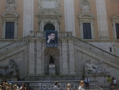 Римский муниципалитет. На балконе портрет Гилада Шалита. Под ним в нише статуя "Ликующий Рим". Слева и справа от статуи символики Тибра и Нила.