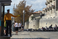 Полицейский движением левой руки указывает вход в крепость Сан-Марино.