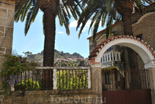 Вид на Монсанту из посёлка Релва через дворик с пальмами при особнячке.