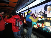 Молодёжь и туристы толпятся возле интерактивной рекламы и карты города.